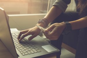 Young woman using credit card making online purchases on laptop